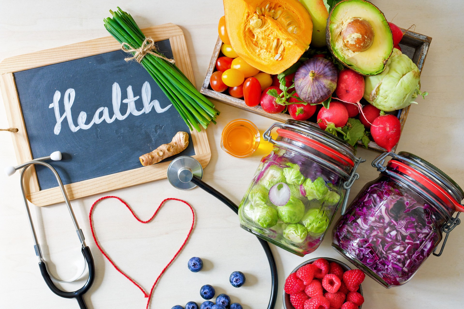 Healthy eating still life shows fresh vegetables, fruits, chalkboard with the word Health and a stethoscope