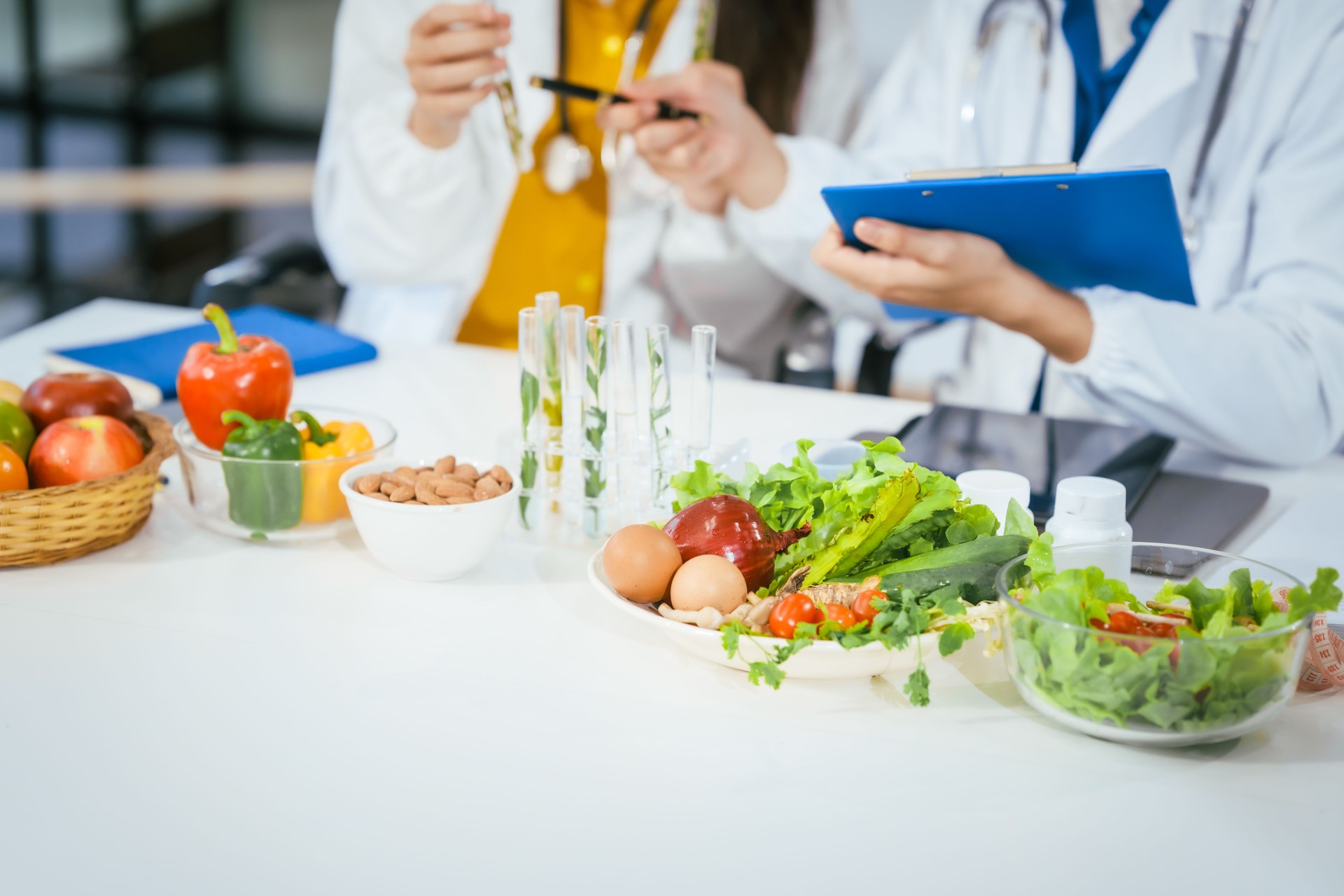 Two nutritionists,female and male, work in a hospital, analyzing vegetable and fruit salads, offering online advice, helping patients embrace clean eating habits and weight control for better health